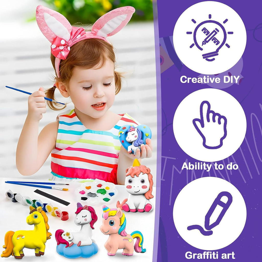 Child wearing bunny ears painting with art supplies, including unicorns and a paintbrush, on a white background.
